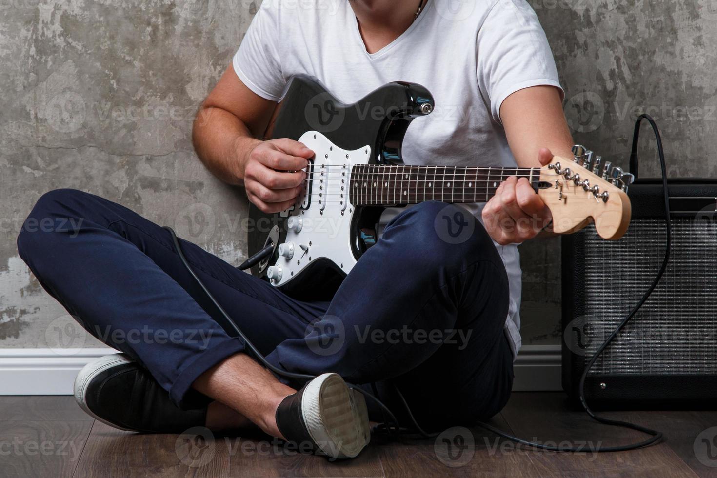 Guy with a guitar sitting on the floor photo