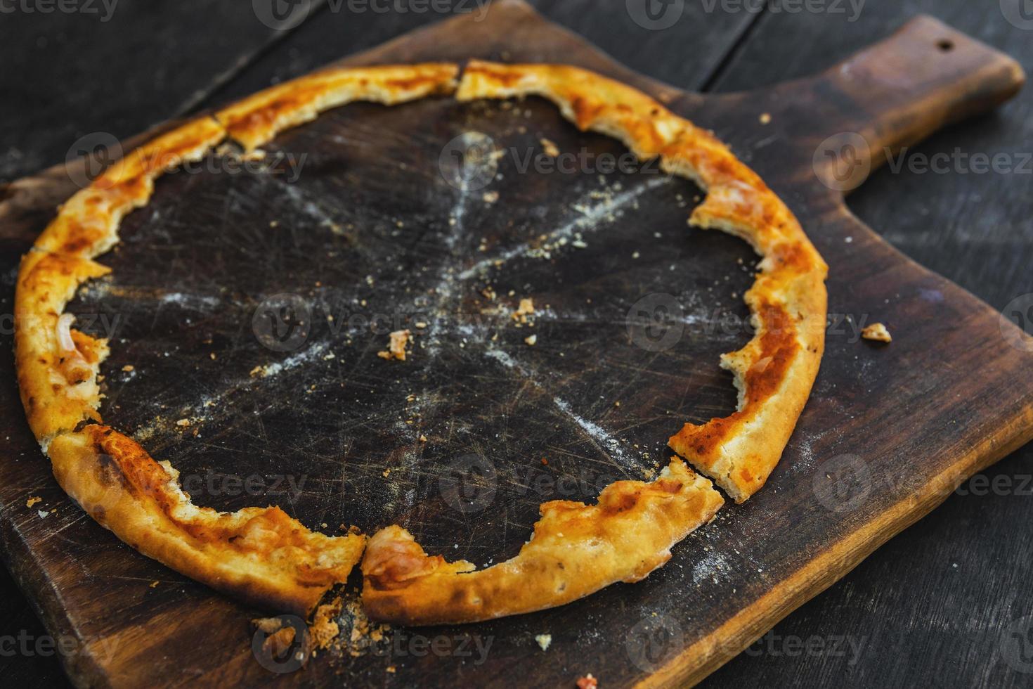 Crunchy crusts of delicious pizza on the wooden board photo