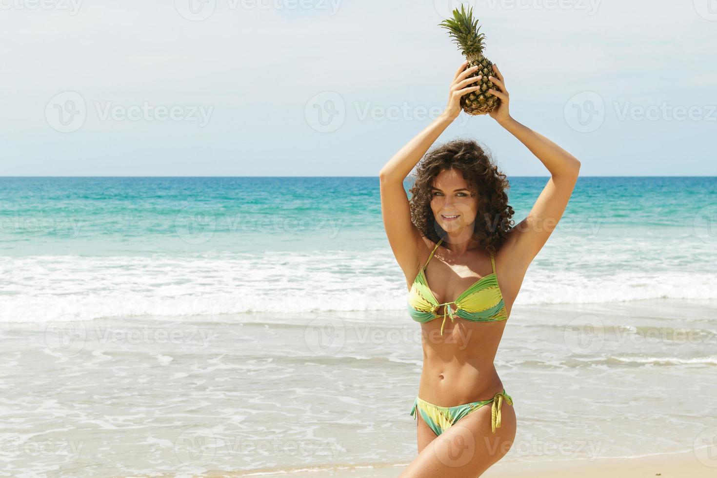 Woman with a pineapple fruit on the beach photo