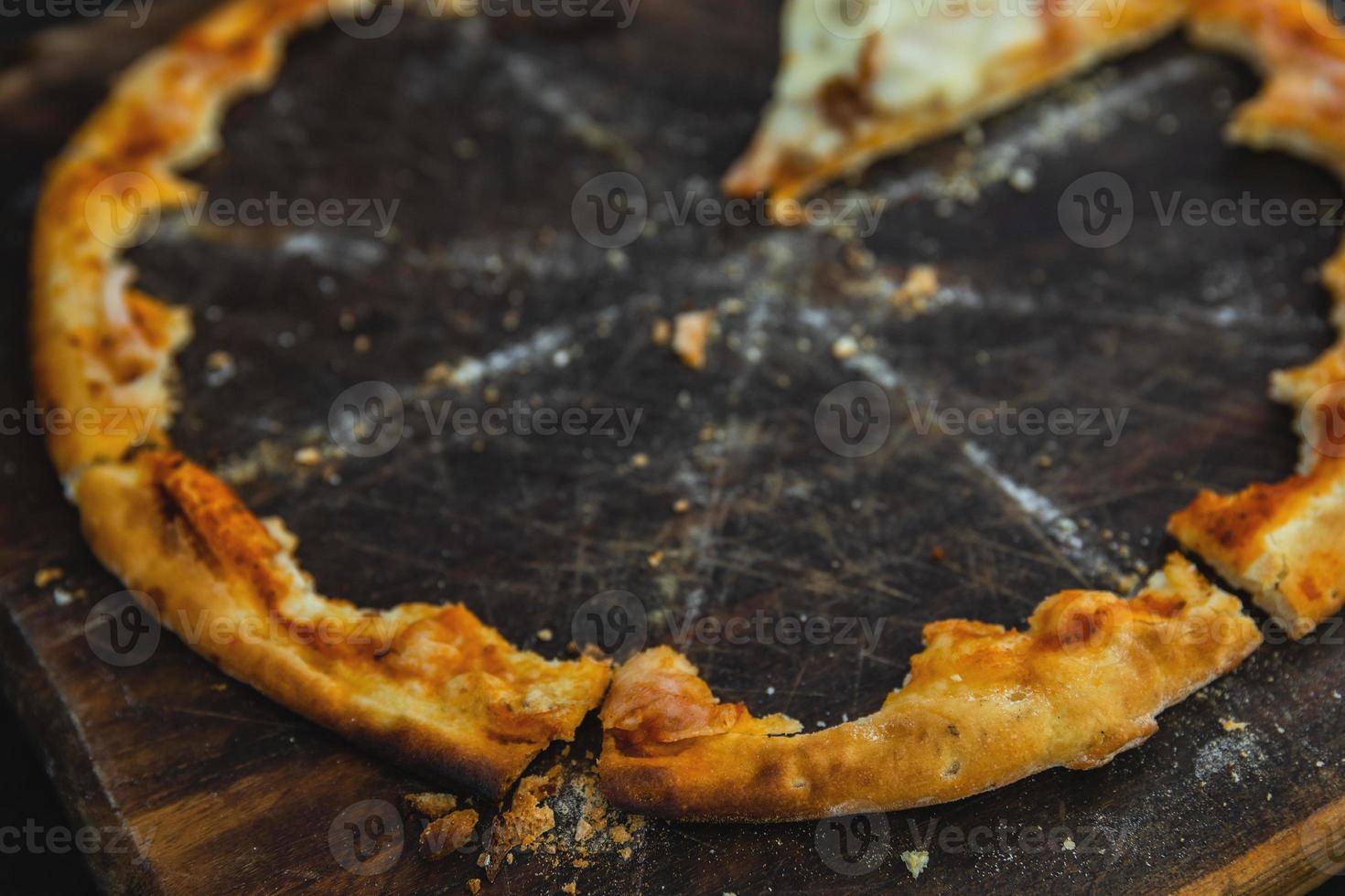 Crunchy crusts of delicious pizza on the wooden board photo