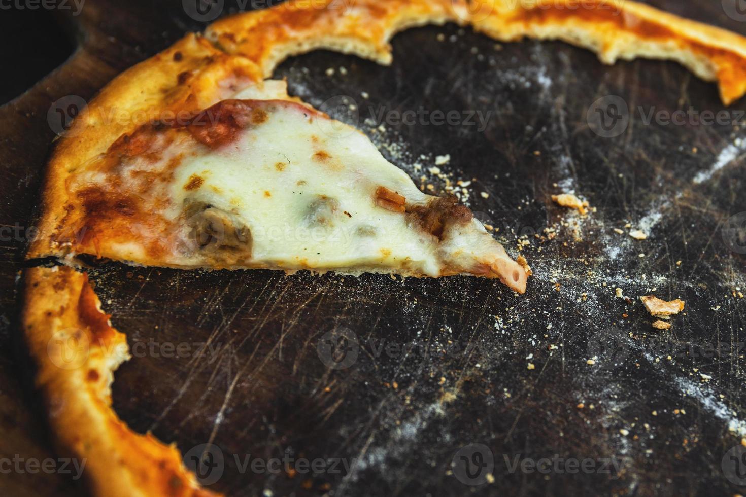 última pieza de deliciosa pizza en la tabla de madera foto