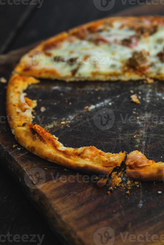 la mitad de una deliciosa pizza al horno en una tabla de madera foto