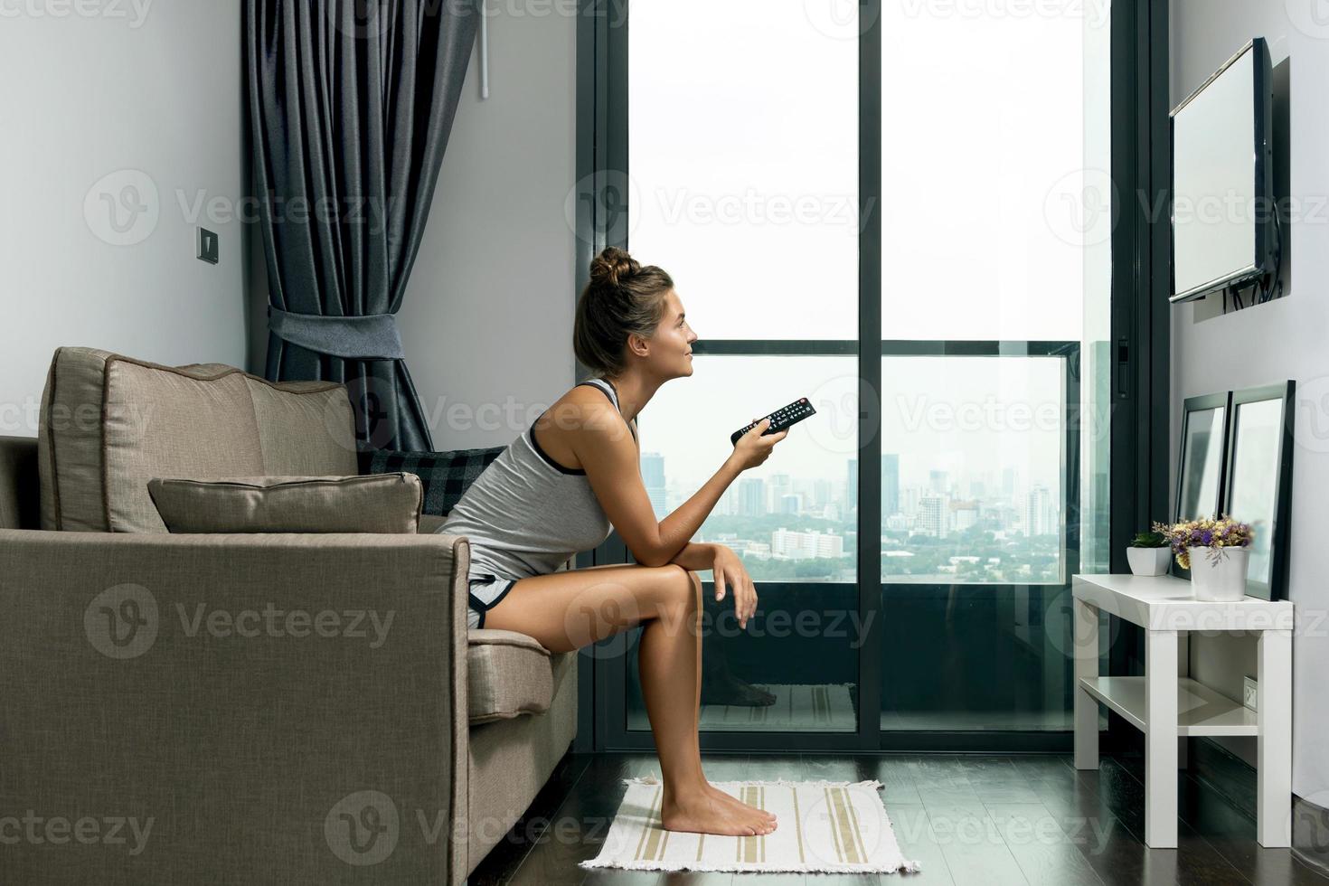 la mujer está sentada en el sofá y viendo la televisión foto