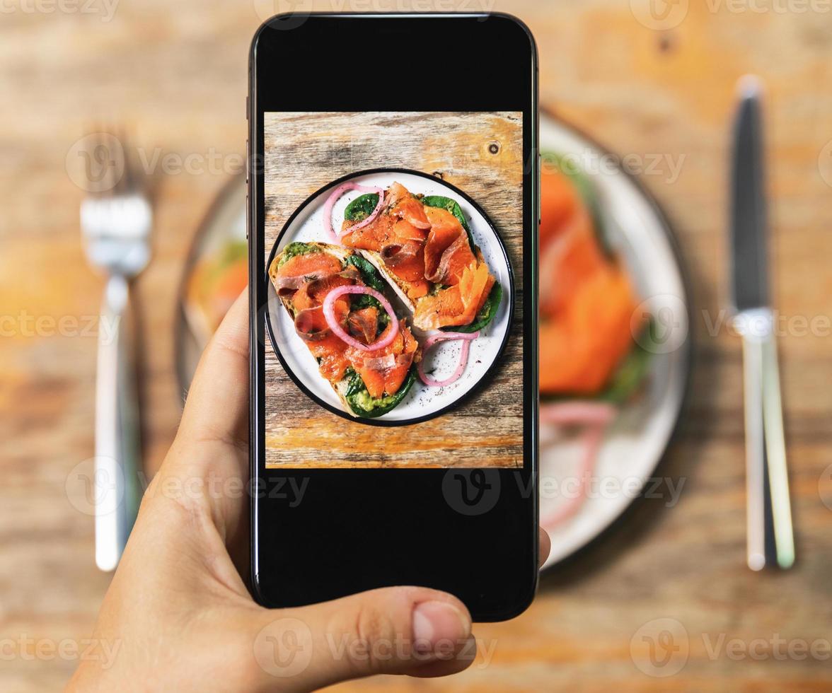 Image on smartphone screen of delicious toasts with a smoked salmon photo