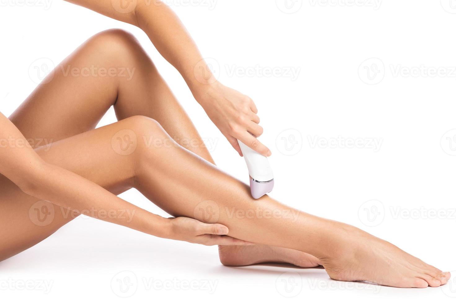 Woman using epilatior device on whtie background photo