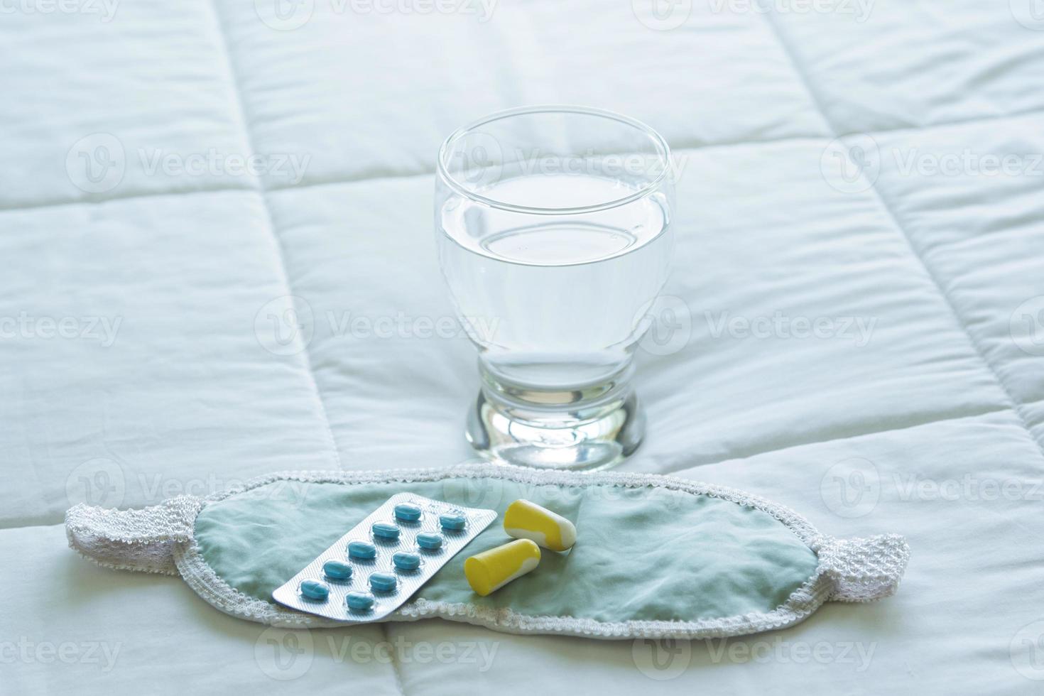 Blister pack of sleeping pills, blindfold and glass of water photo