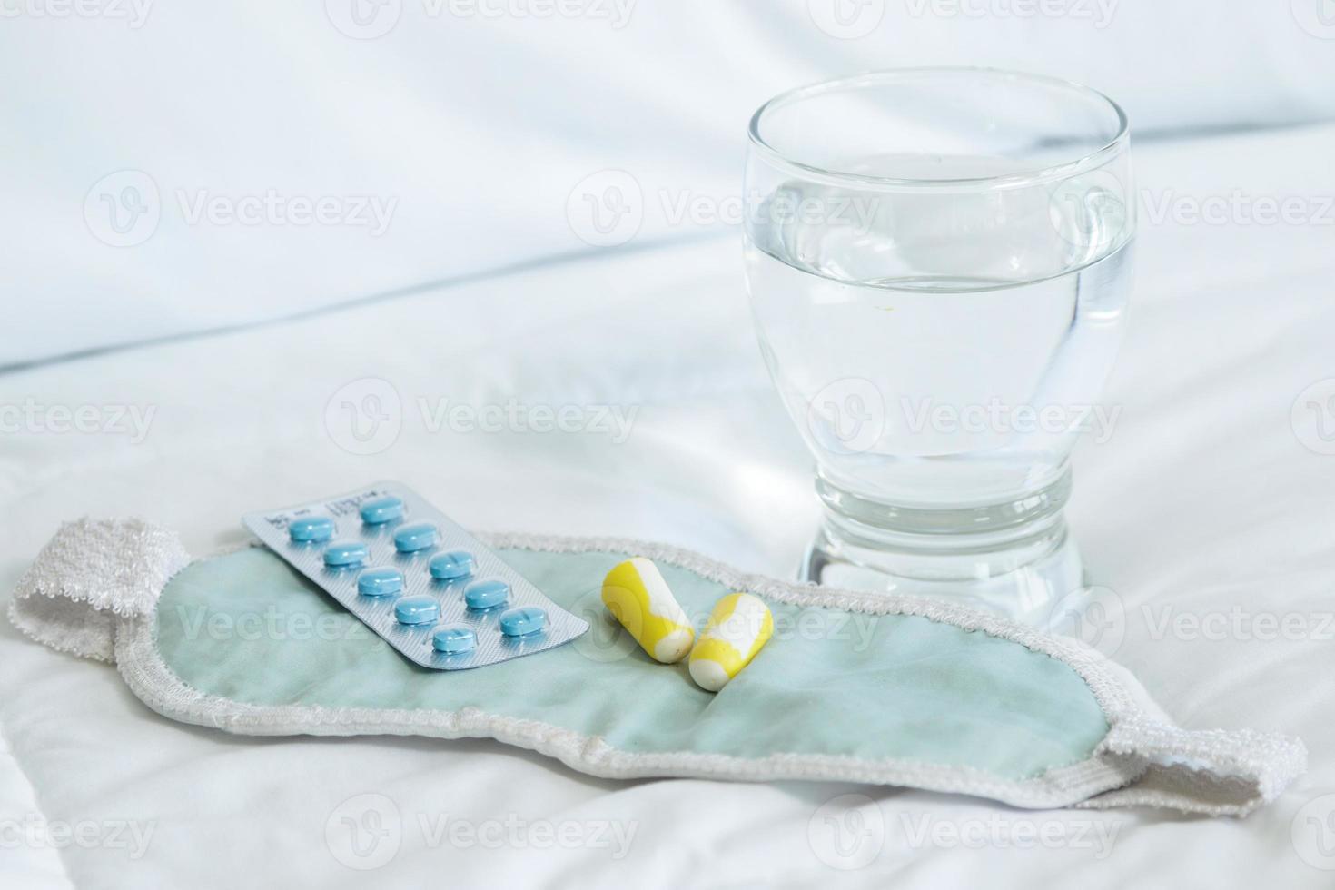 Blister pack of sleeping pills, blindfold and glass of water photo