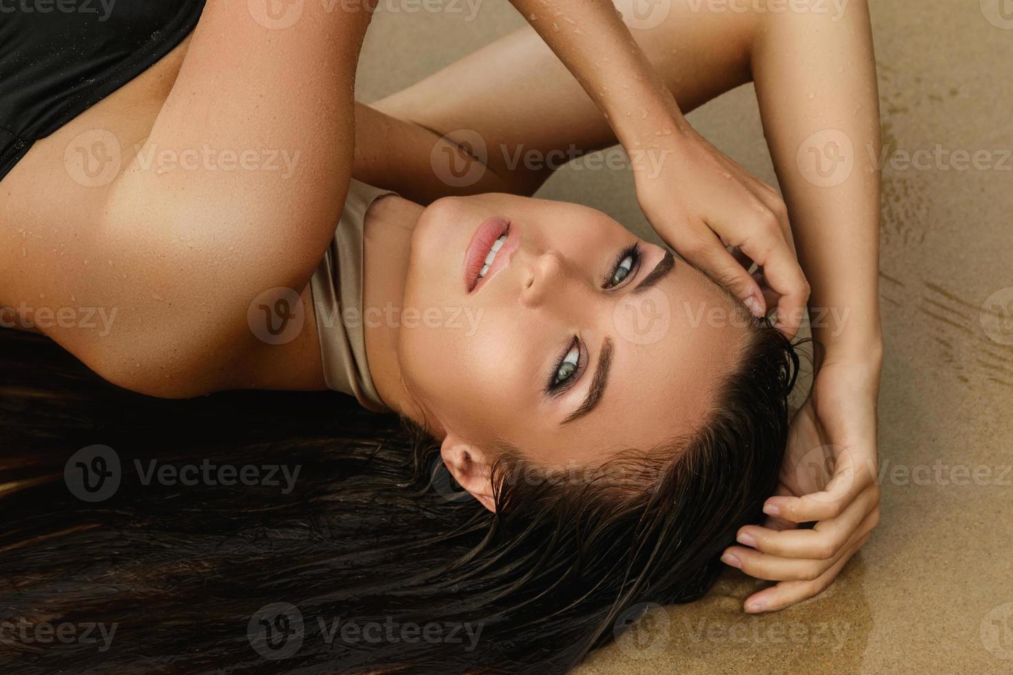 Woman is lying in wet sand on the beach photo