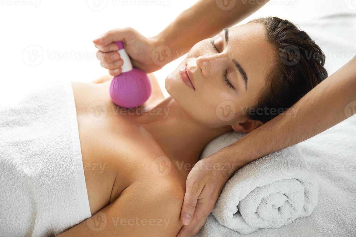 Woman is enjoying Asian massage therapy with herbal compress photo