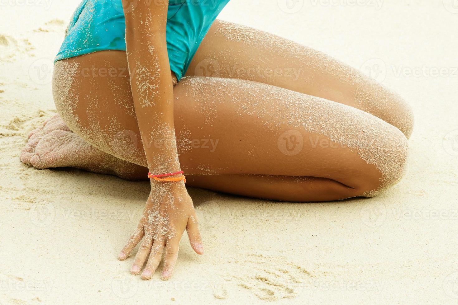 Sexy female hips covered with a sand on the beach photo