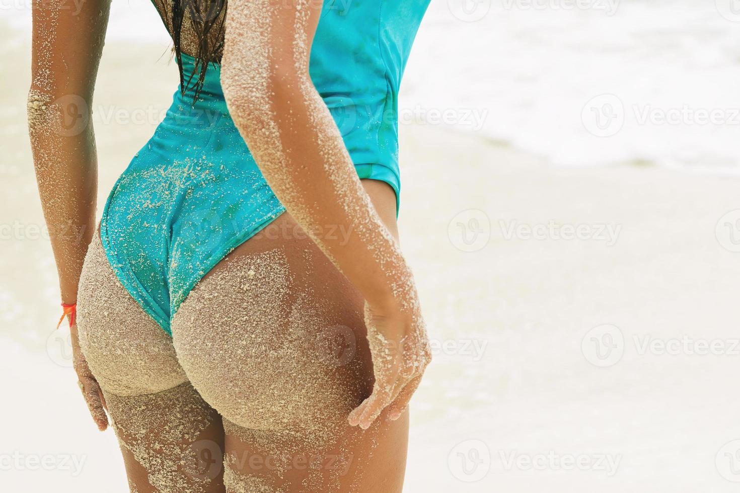 sexy mujer nalgas cubiertas de arena en la playa foto