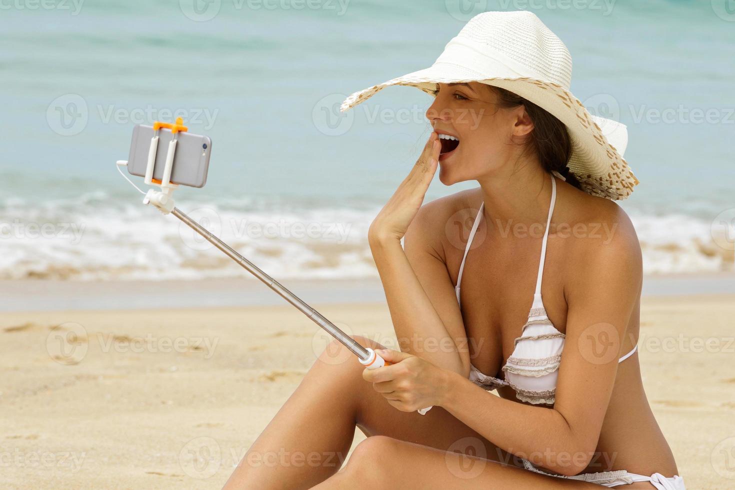 Beautiful woman is taking selfie on the beach photo