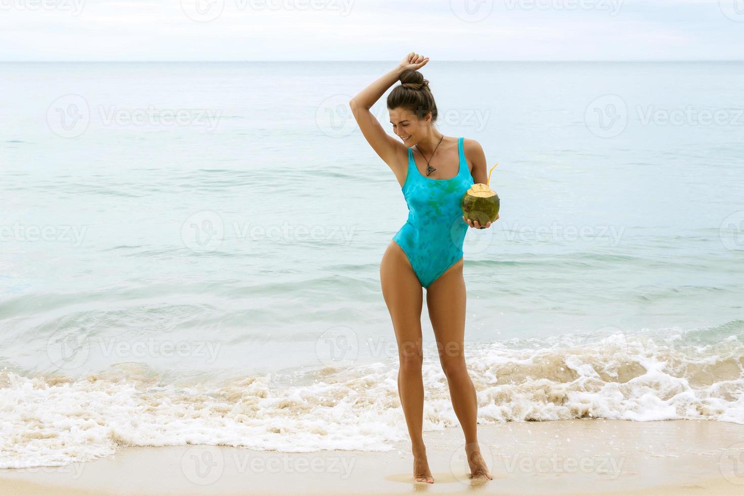 Happy woman with a coconut on the beach photo