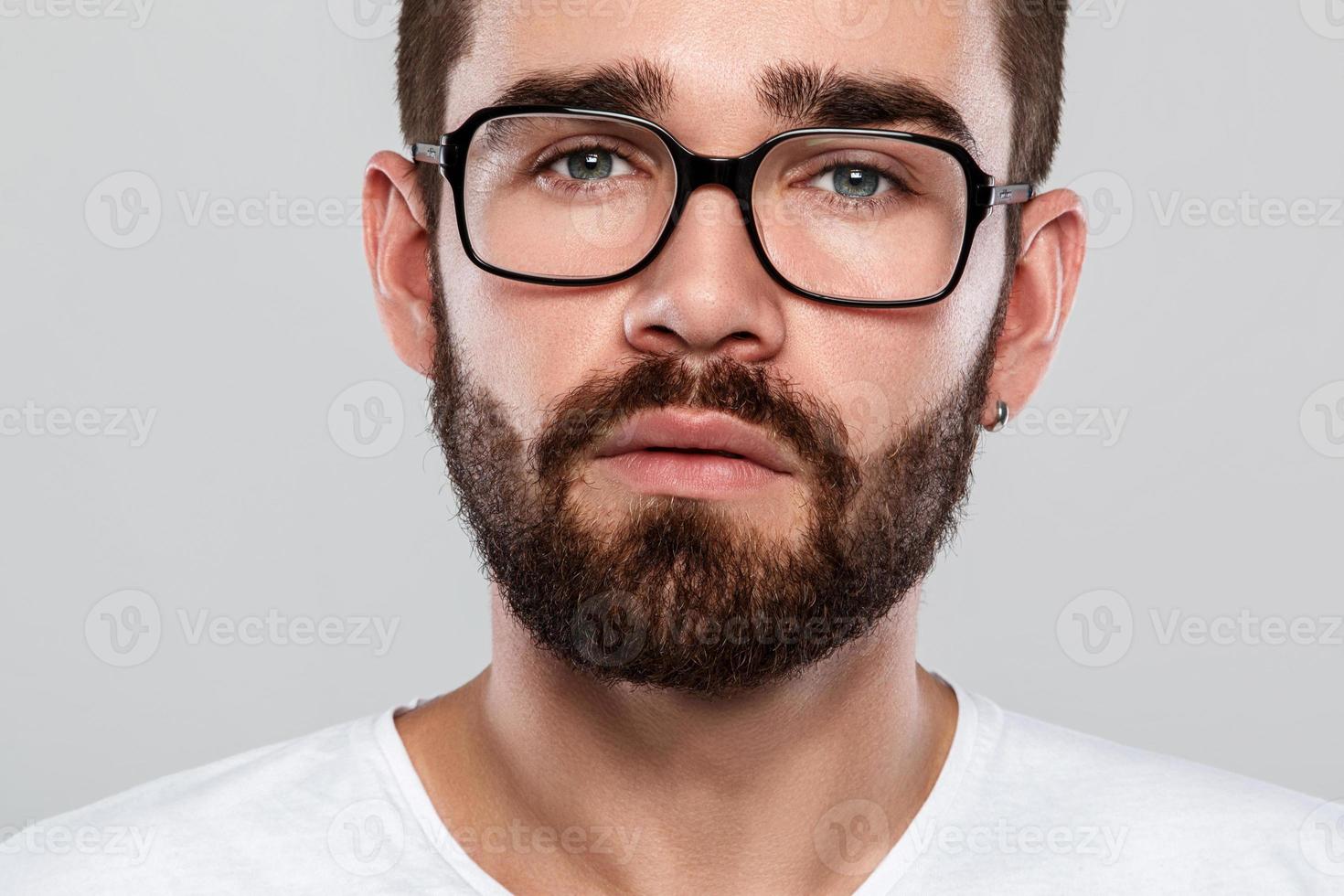 Stylish bearded man in eyeglasses against gray background photo