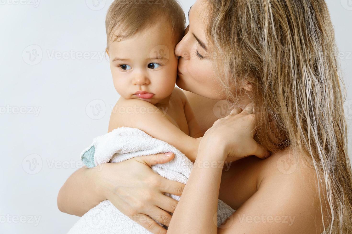 Young and happy mother and her cute little baby after bathing photo