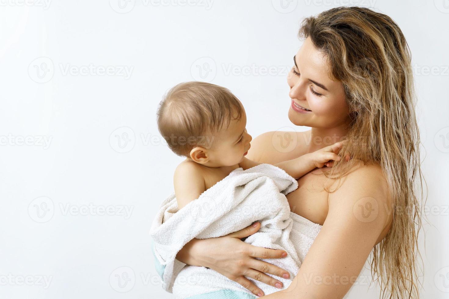 Young and happy mother and her cute little baby after bathing photo