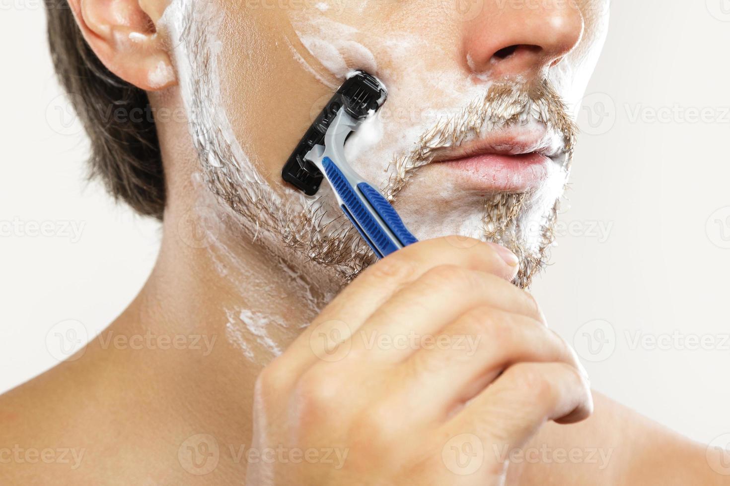 Man with a safety razor and shaving cream on his face photo