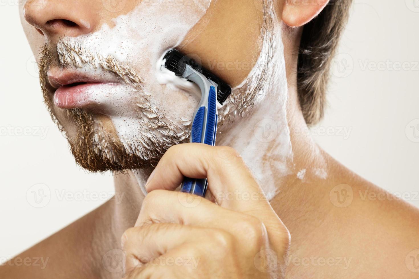 hombre con una maquinilla de afeitar de seguridad y crema de afeitar en la cara foto