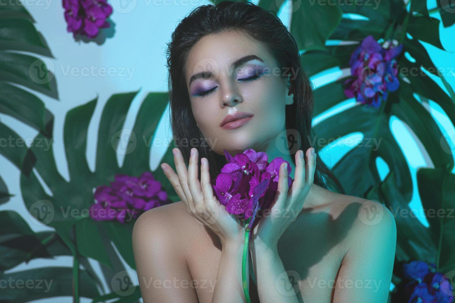 Young and beautiful woman with perfect smooth skin is holding orchid flowers photo