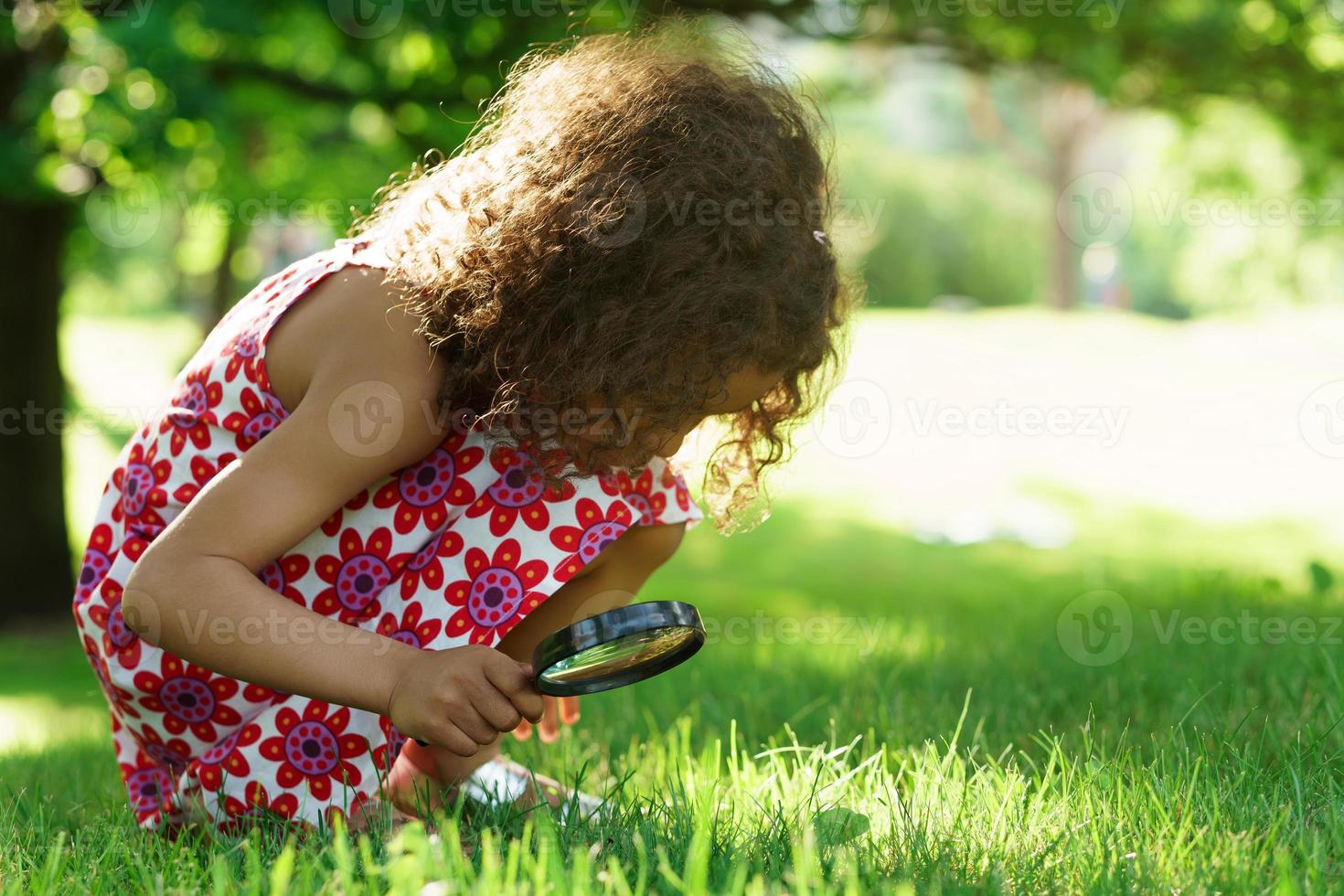 Little black girl with looking through magnifying glass photo