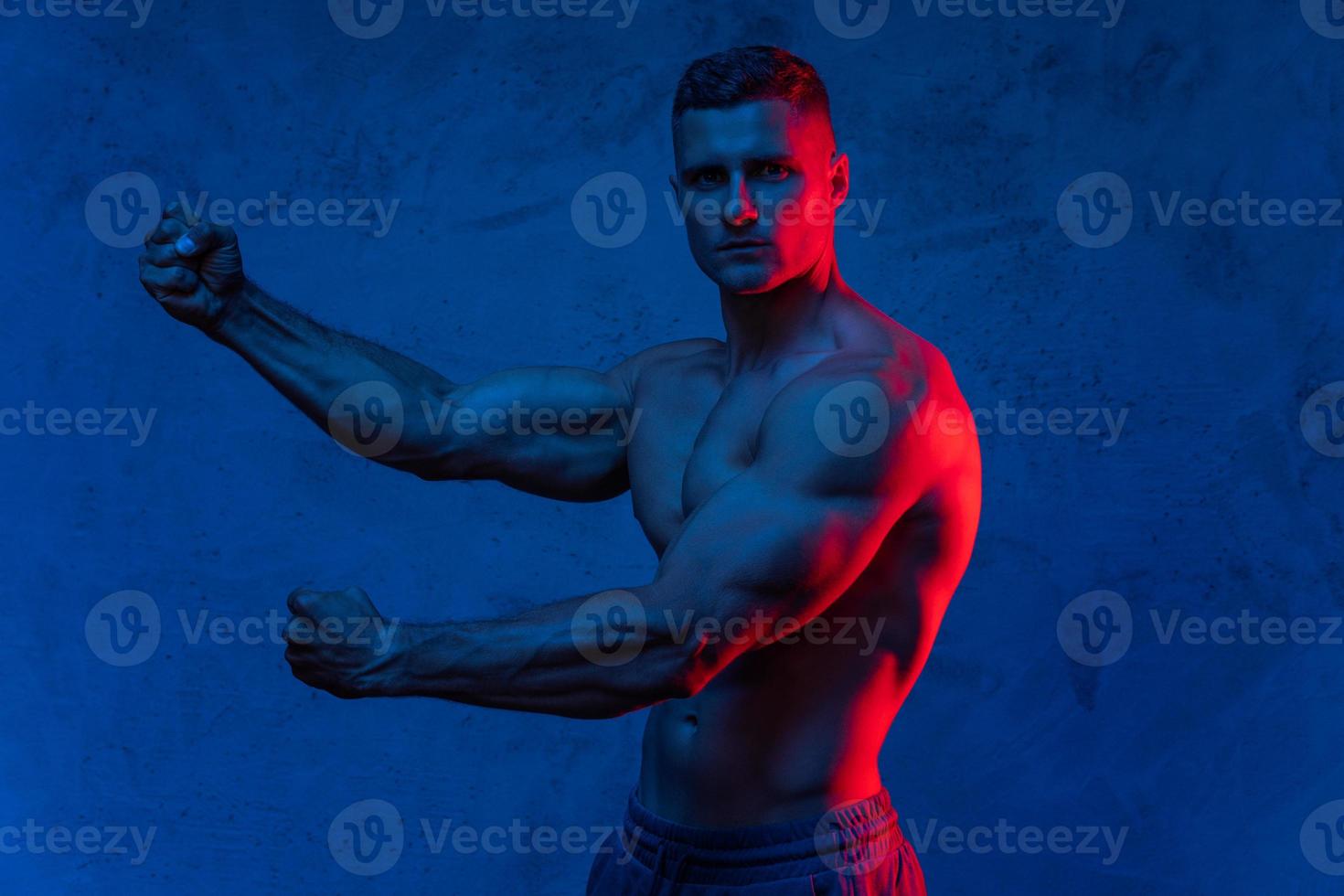 Muscular man posing in the colorful light photo