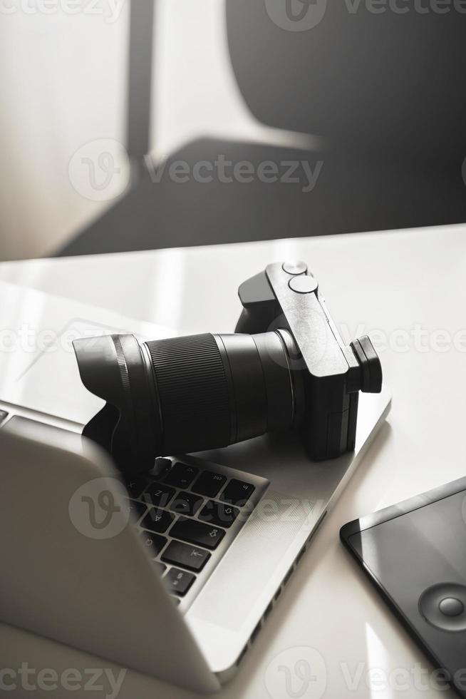 Photographer's workplace with a mirrorless camera, laptop and graphics tablet photo