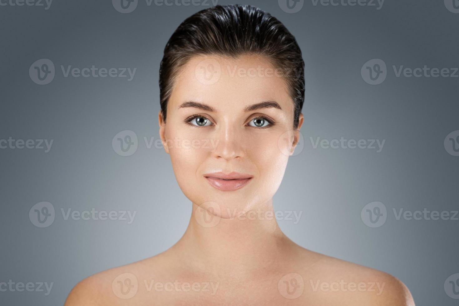 Young beautiful woman with perfect skin on gray background photo