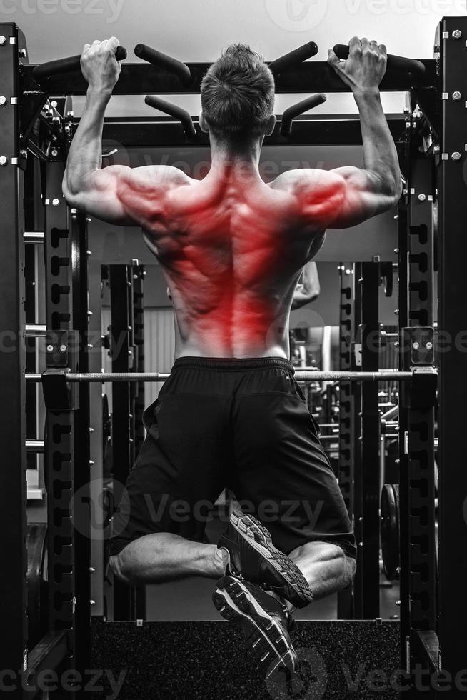 Back specialization in bodybuilidng. Man doing pull-ups on a horizontal bar photo