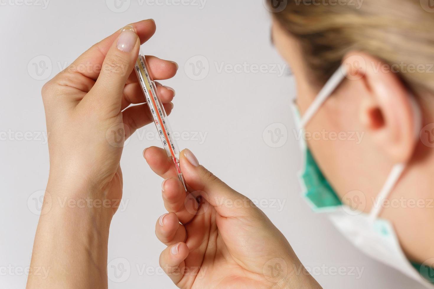 Woman is looking on the thermometer after body temperature measurement photo