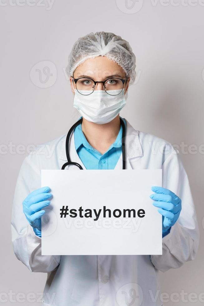 Female doctor is holding paper with the hashtag stayhome photo
