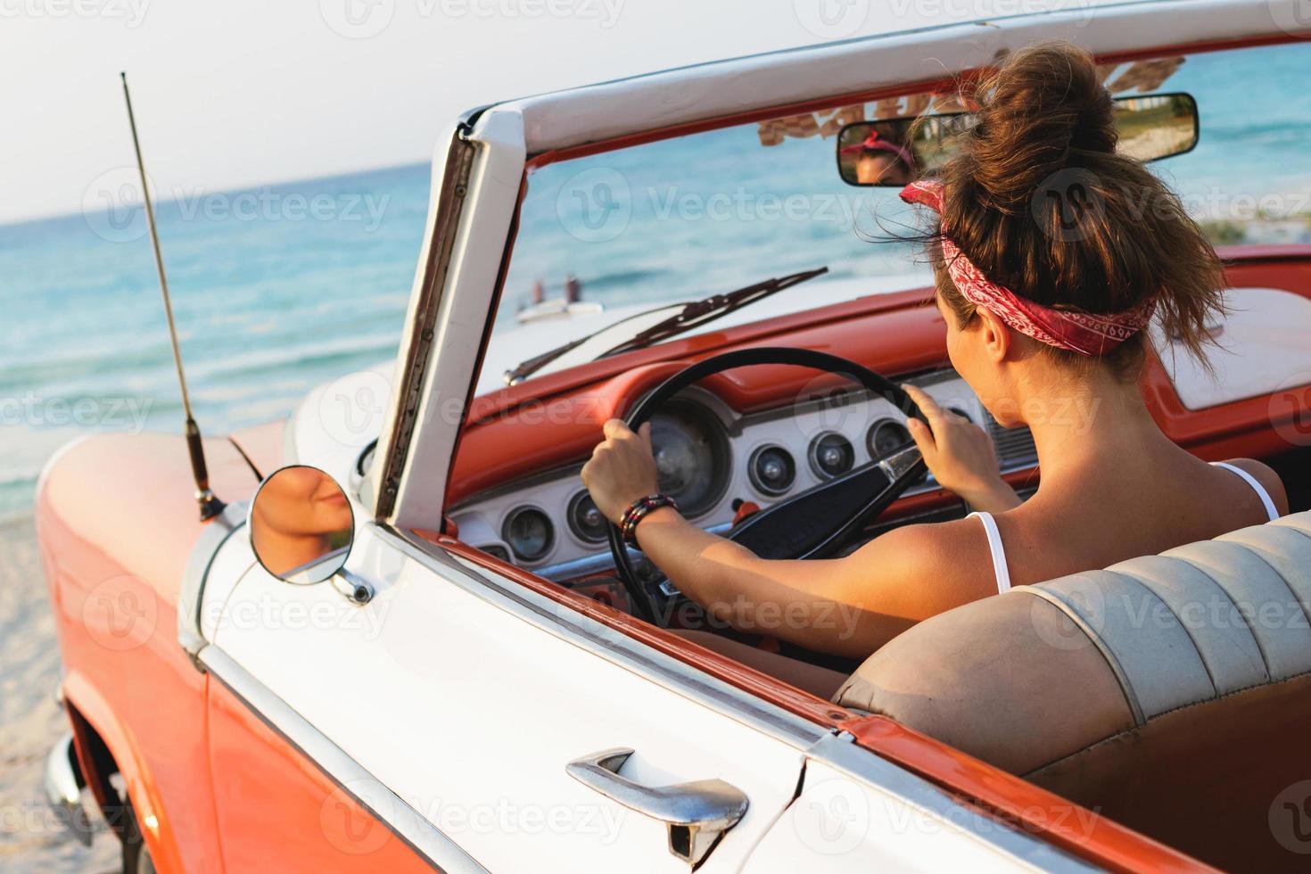 mujer hermosa y feliz dentro de un coche cabriolet retro foto