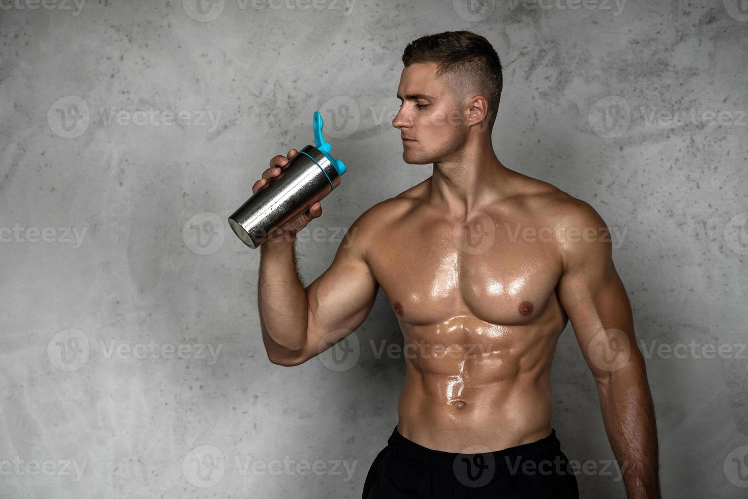 hombre musculoso bebiendo proteína de suero u otro suplemento deportivo foto