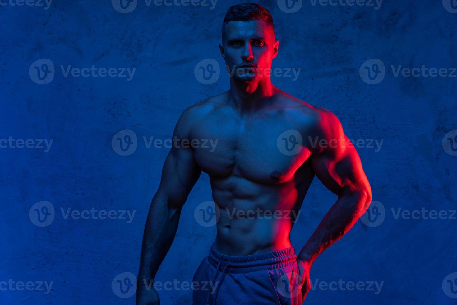 Muscular man posing in the colorful light photo