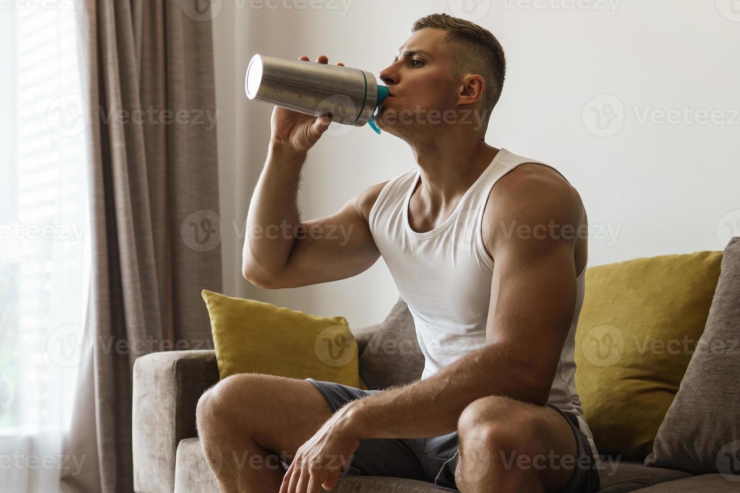 hombre bebiendo batido de proteínas después de hacer ejercicio en casa foto