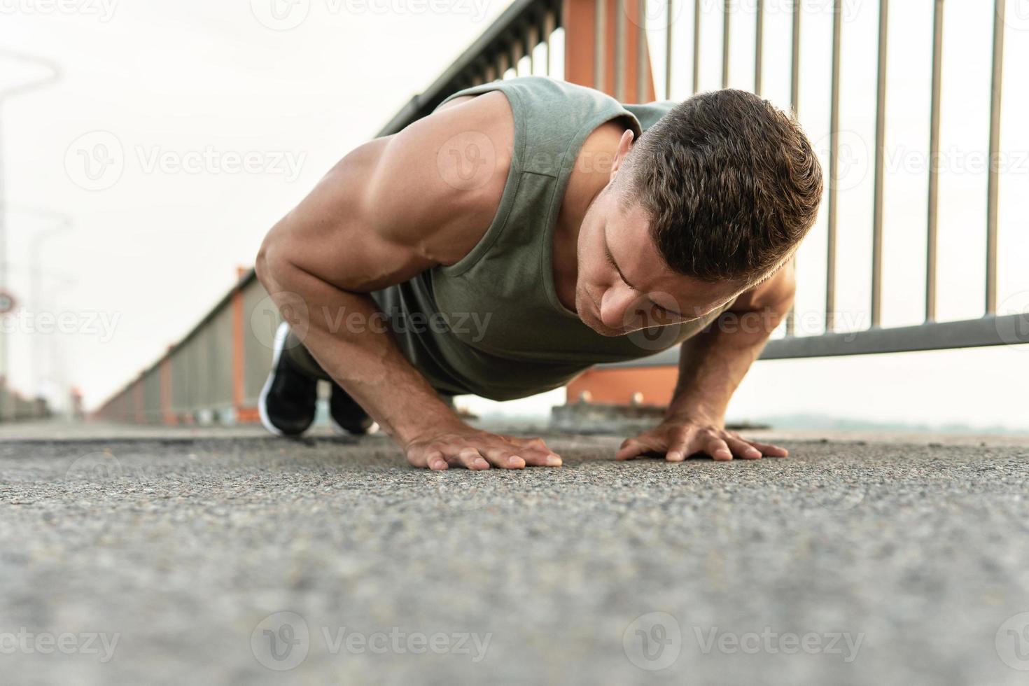 Muscular man is doing push-ups during calisthenic workout on a street photo