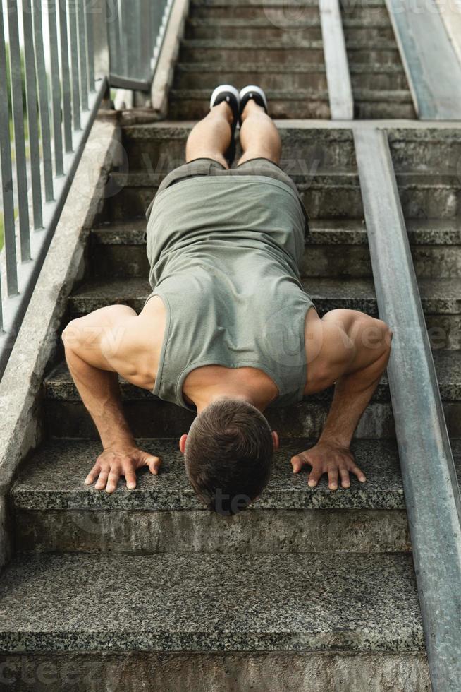 Muscular man is doing push-ups during calisthenic workout on a street photo