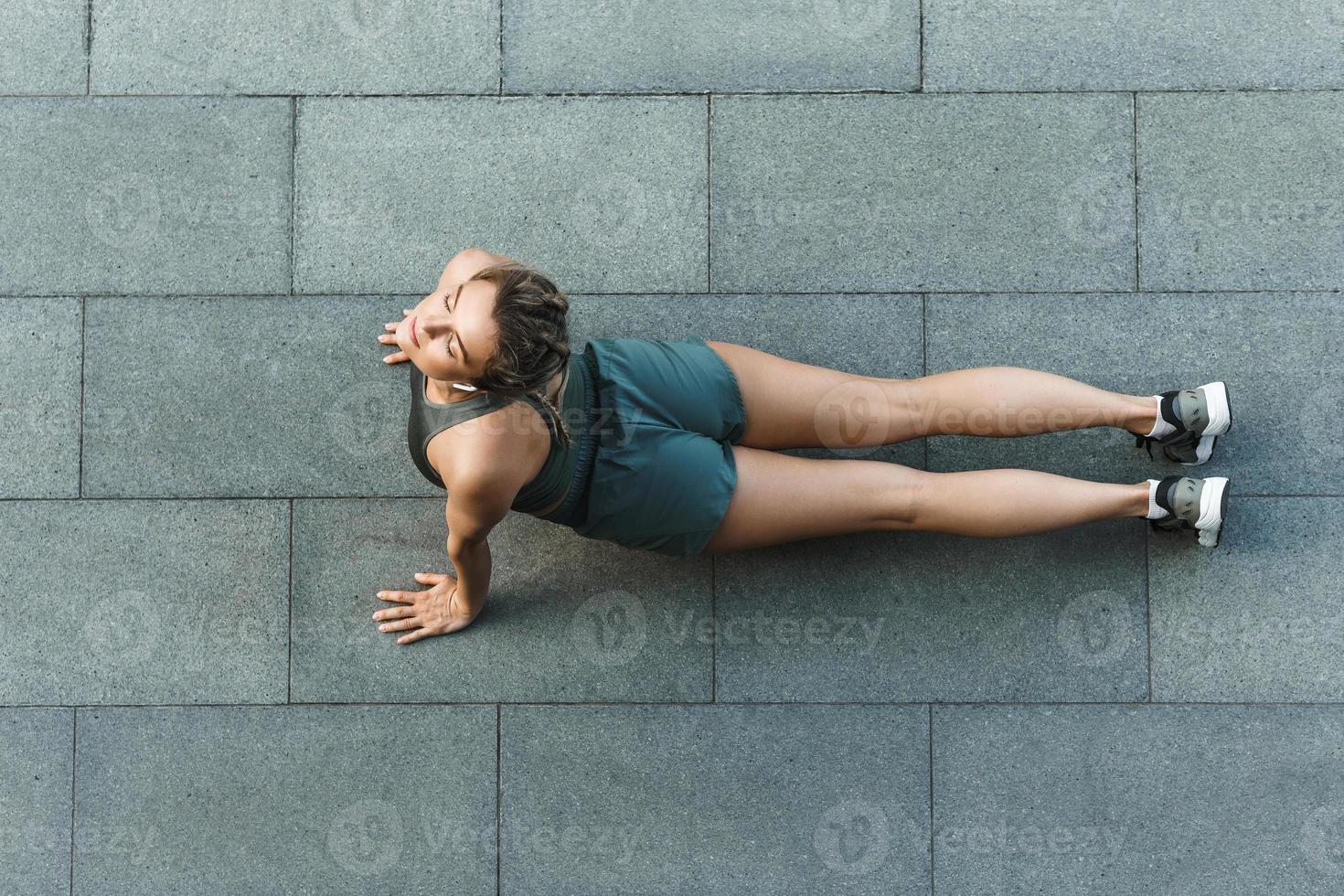 Athletic woman is doing yoga exercises during workout on a street photo
