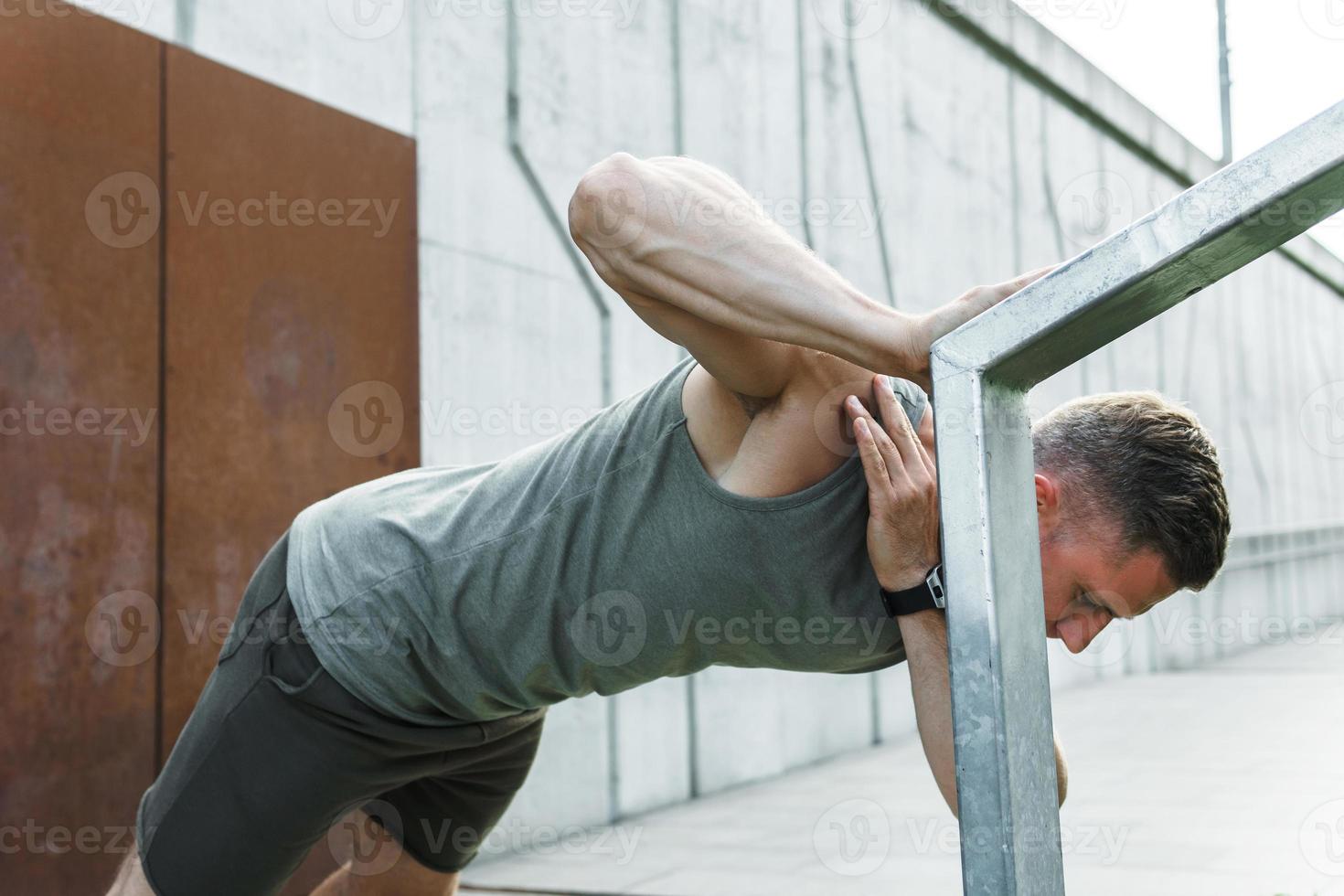 Handsome muscular man doing one arm push-up photo