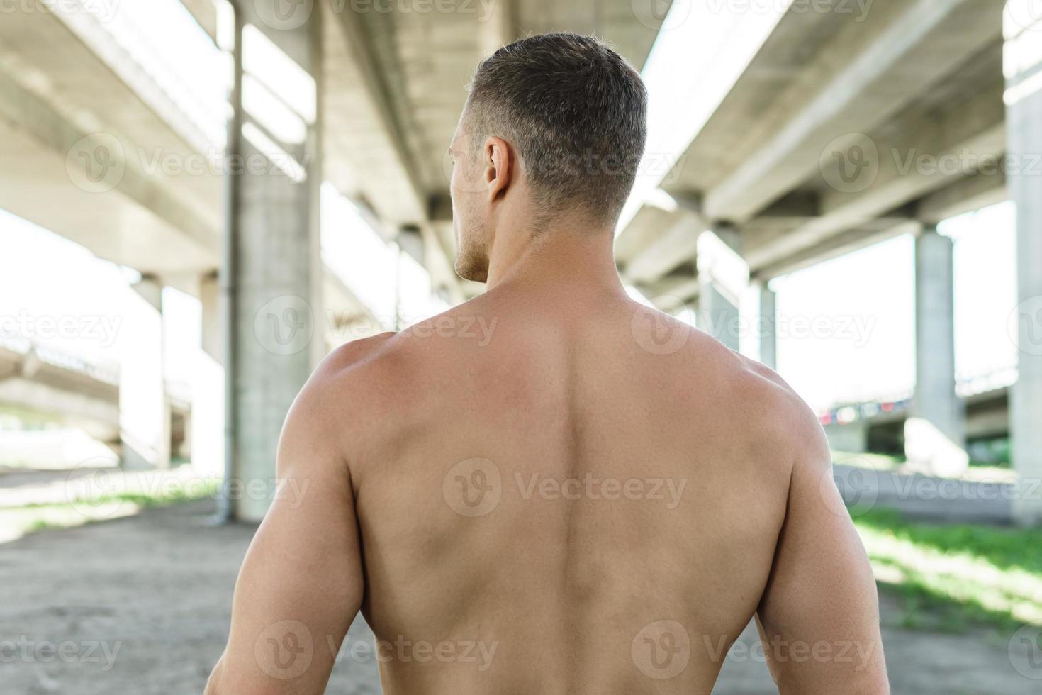 Muscular man under a bridge during his fitness street workout photo