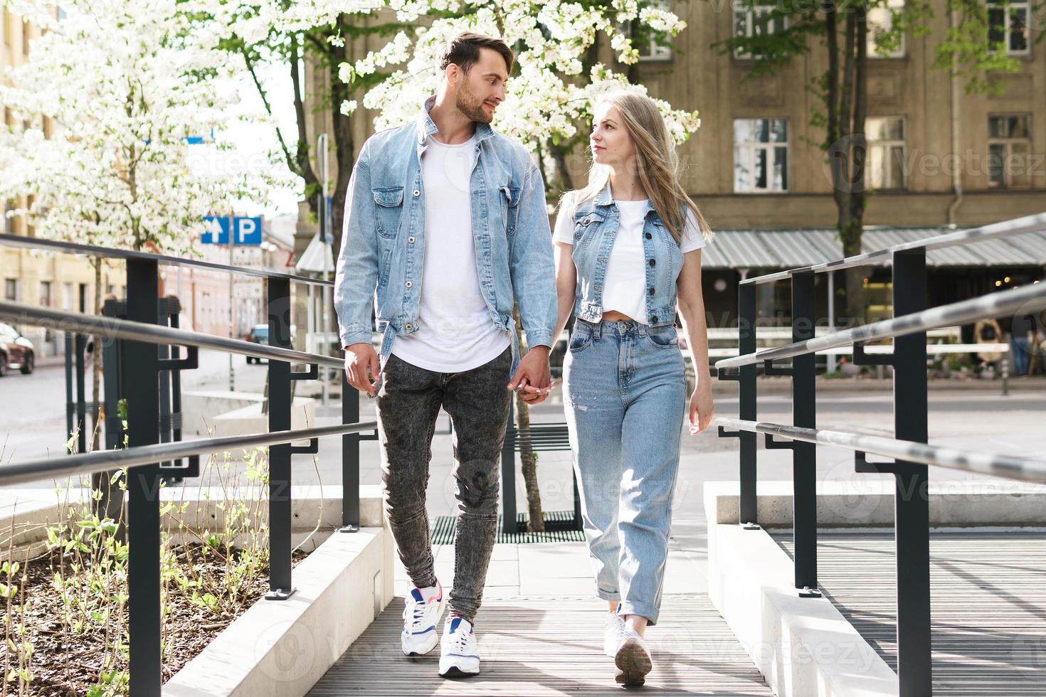 Loving couple wearing denim outfits walking during their date on a city street photo