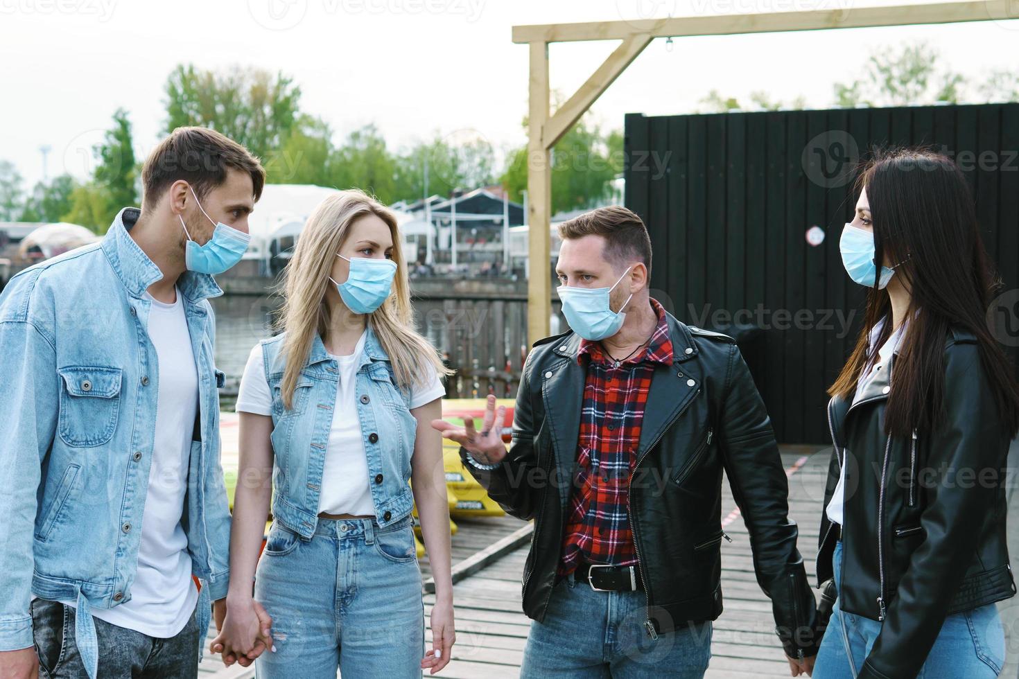 Group of friends wearing prevention masks during their meeting outdoors. photo