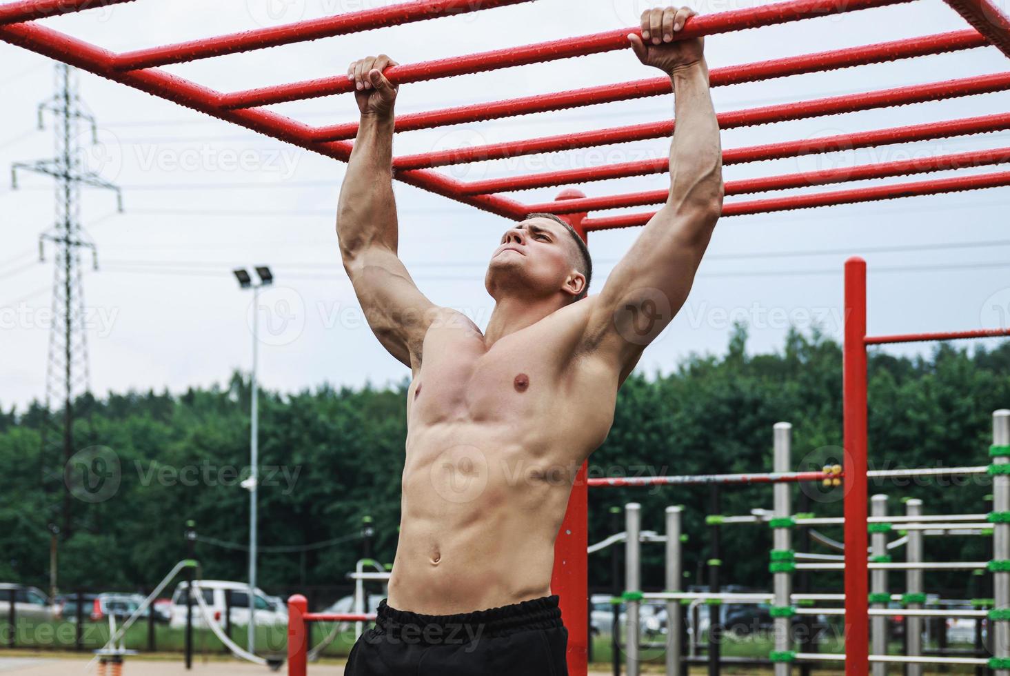 Muscular man doing pull-ups on horizontal bar photo