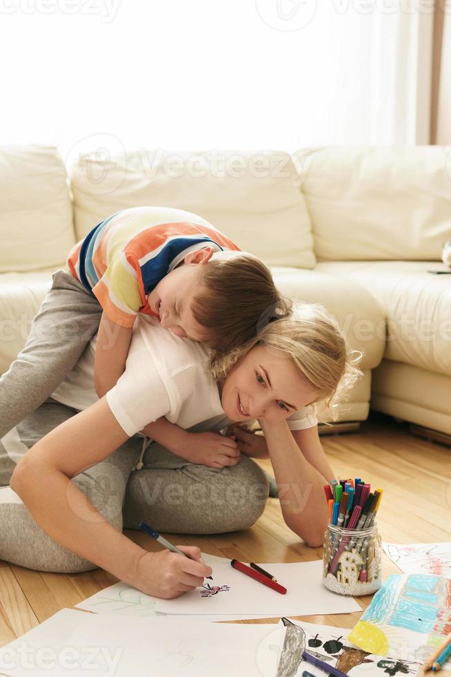 Happy mother and son are drawing together at home photo