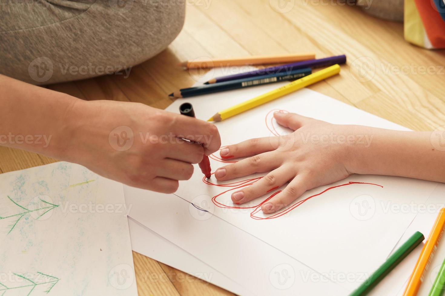 Mother is drawing outline of her son's palm photo