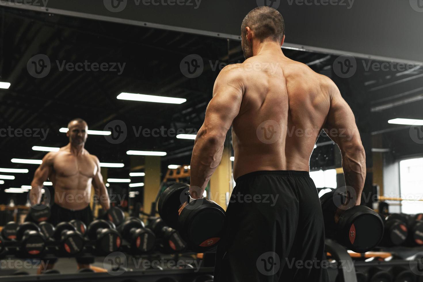 Muscular bodybuilder in a free weights zone in the gym photo