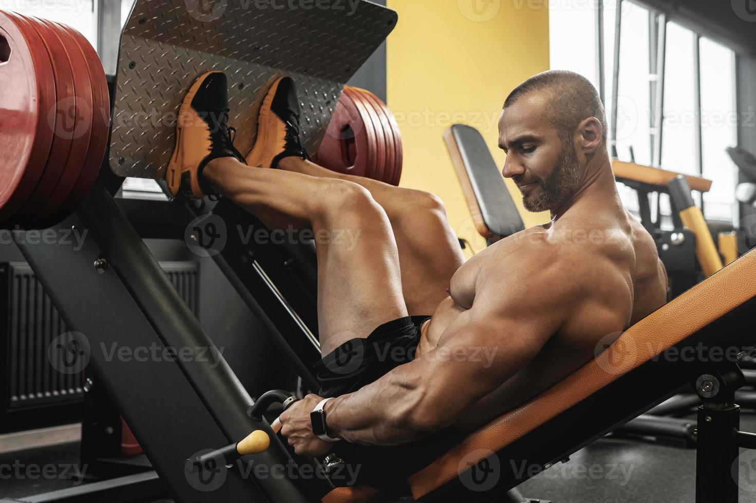 Bodybuilder doing a seated leg press exercise in a gym photo