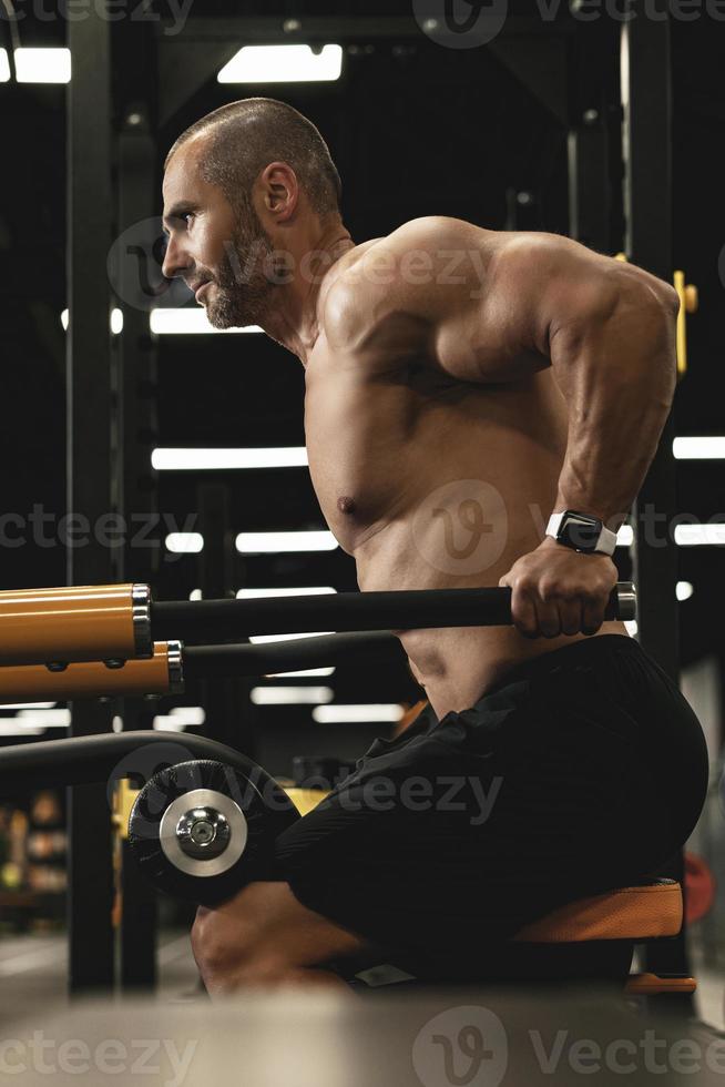 Muscular bodybuilder doing dips for triceps and chest muscles in the gym photo