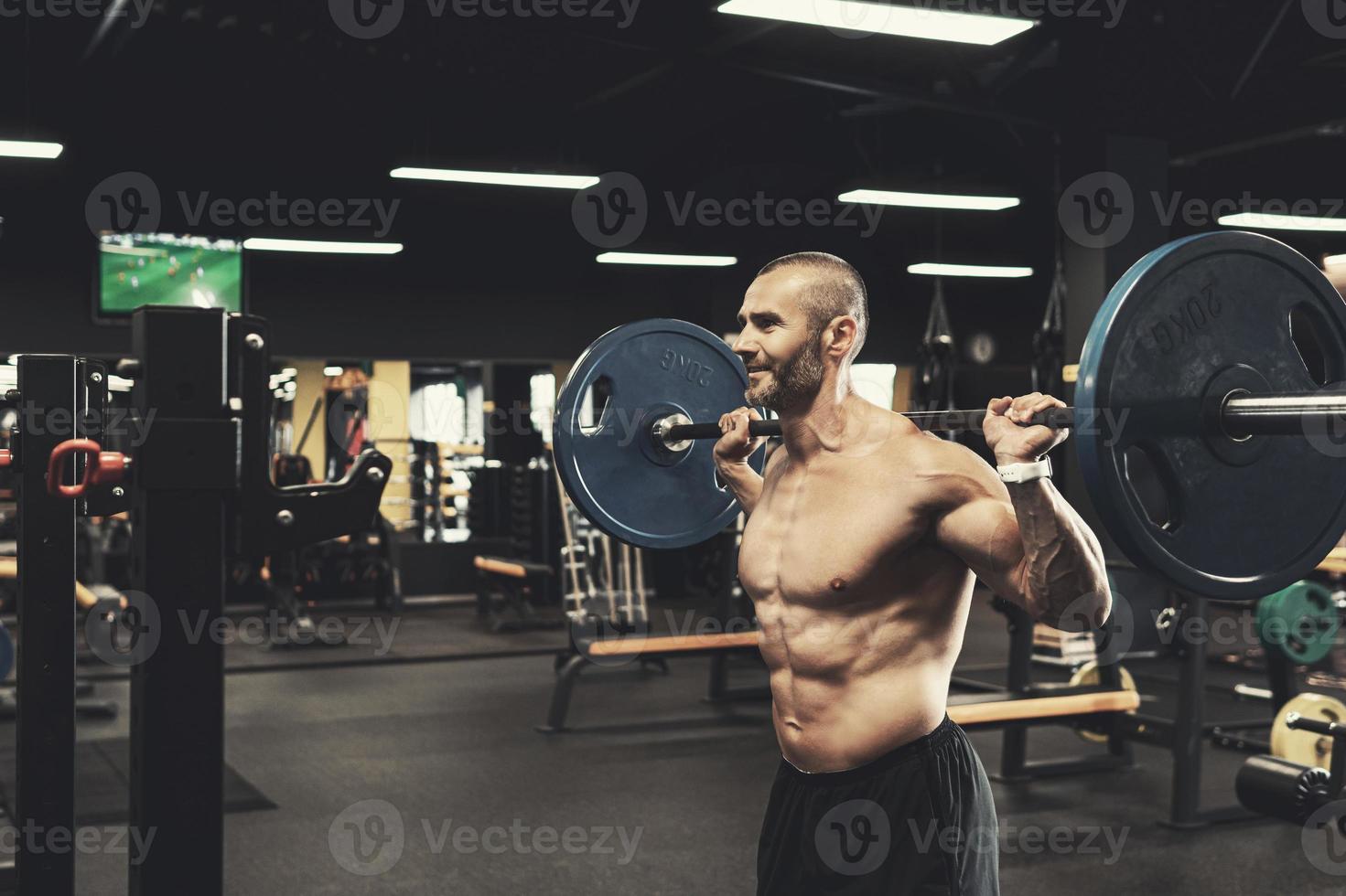 Bodybuilder during his workout with a barbell in the gym photo