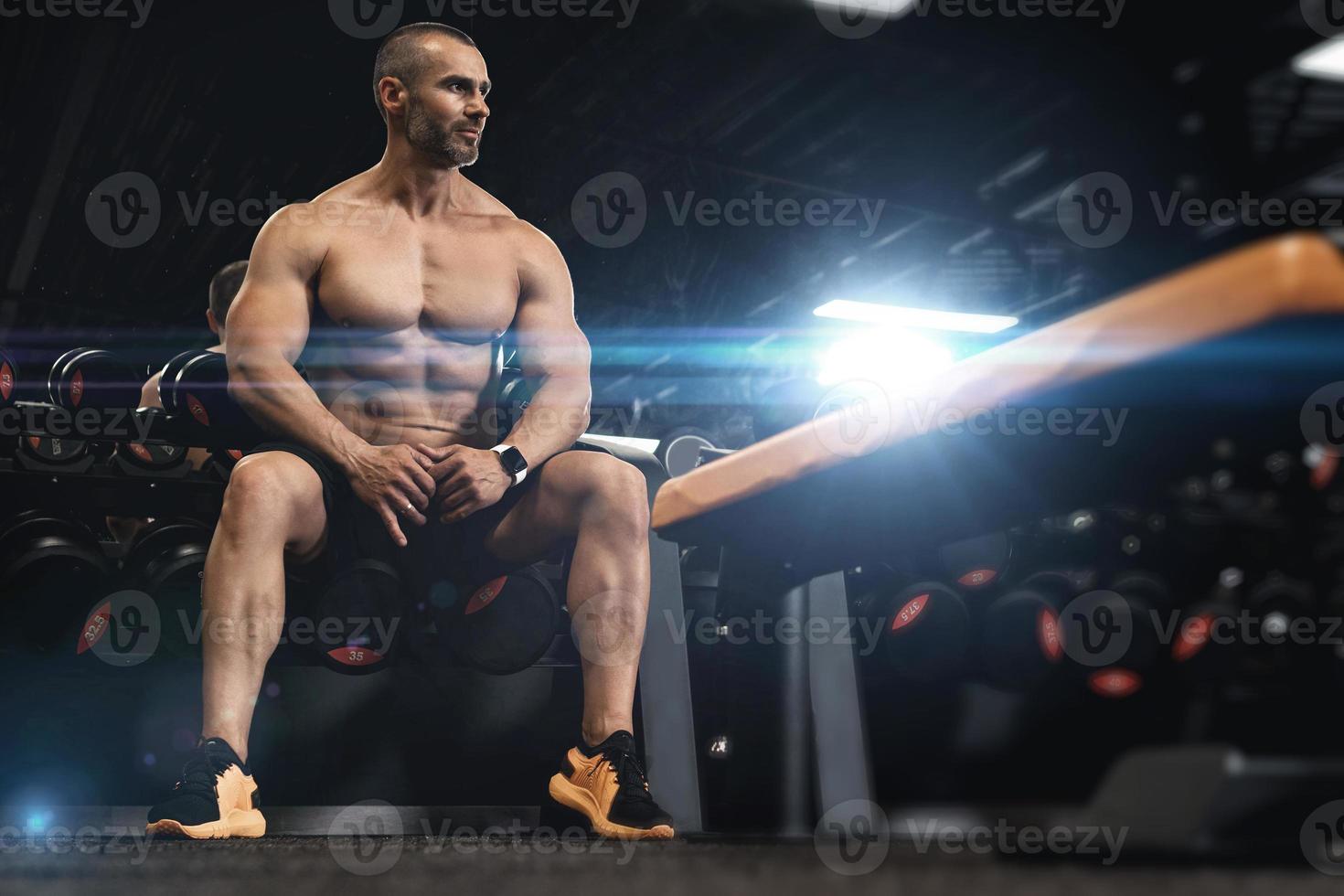 culturista musculoso en una zona de pesas libres en el gimnasio foto