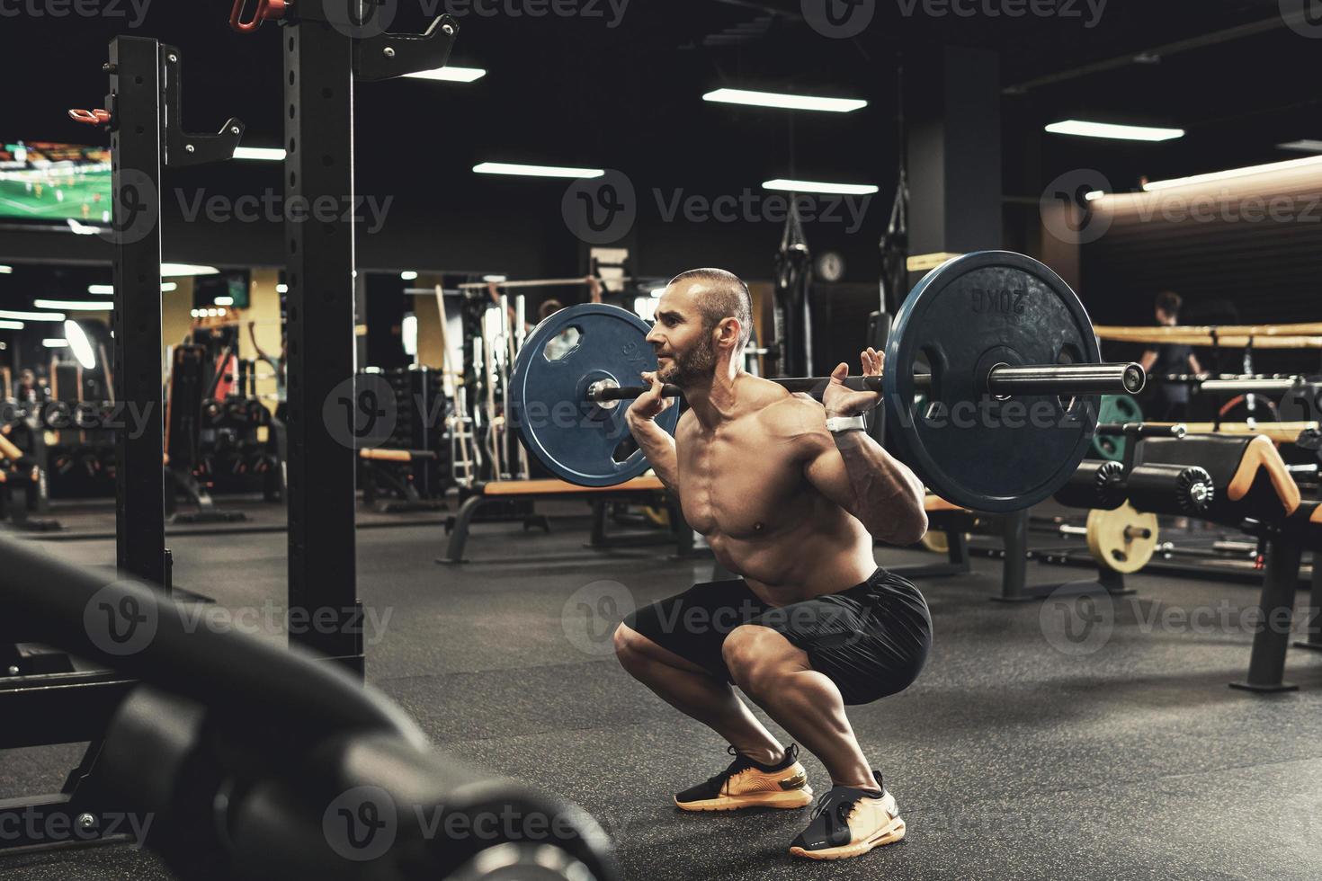 Bodybuilder during his workout with a barbell in the gym photo